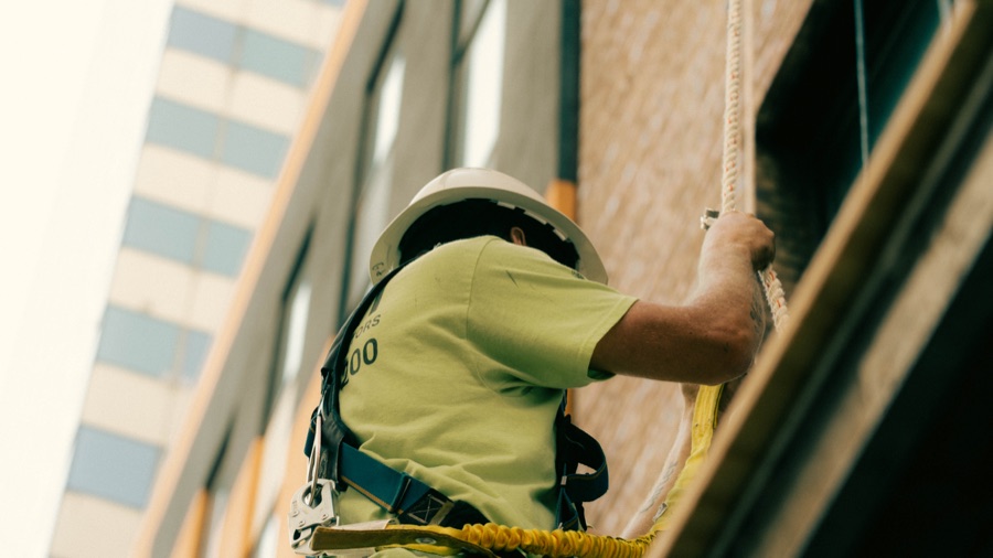 A worker suspended against a sunlit building