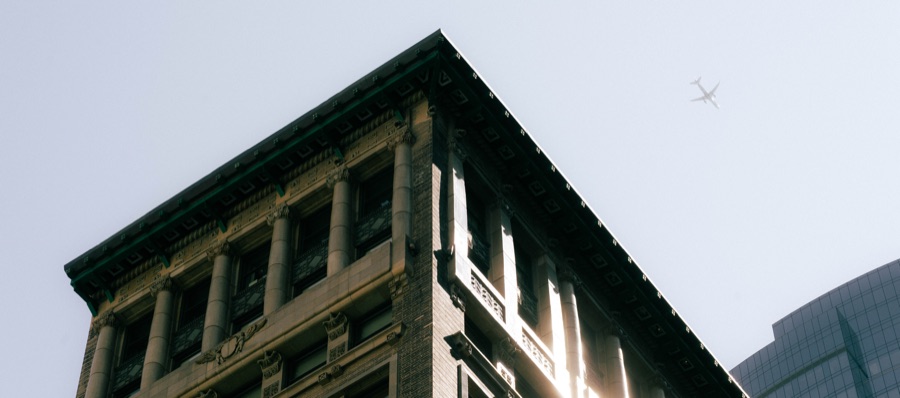 An airplane above a sunlit building cornice
