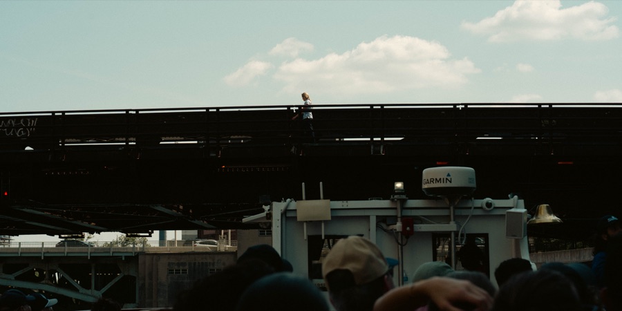A lone pedestrian crossing above a river boat