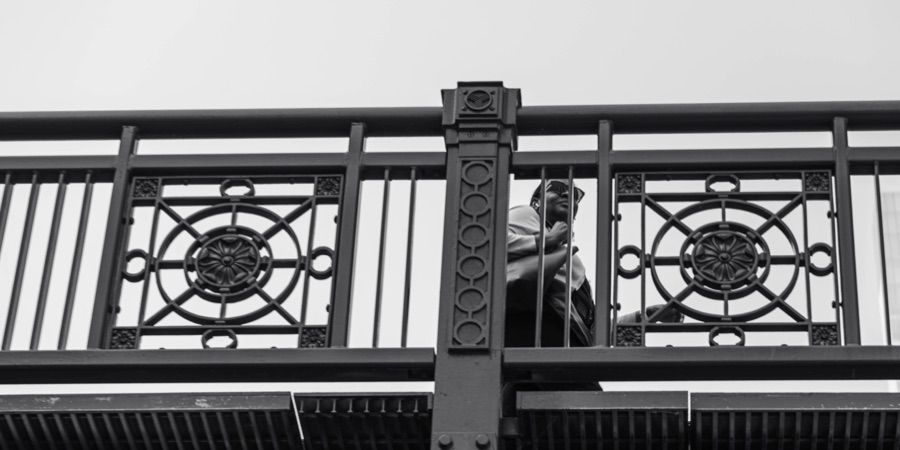 A passerby framed by an ornate bridge railing