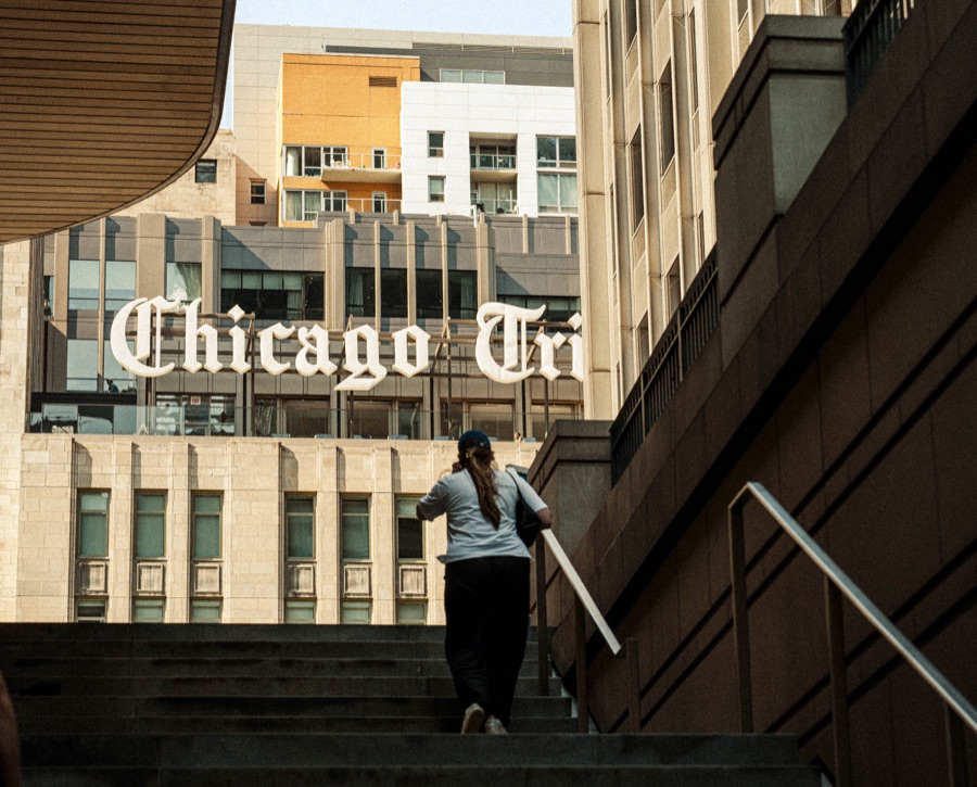 A person walking up steps beside the Tribune sign